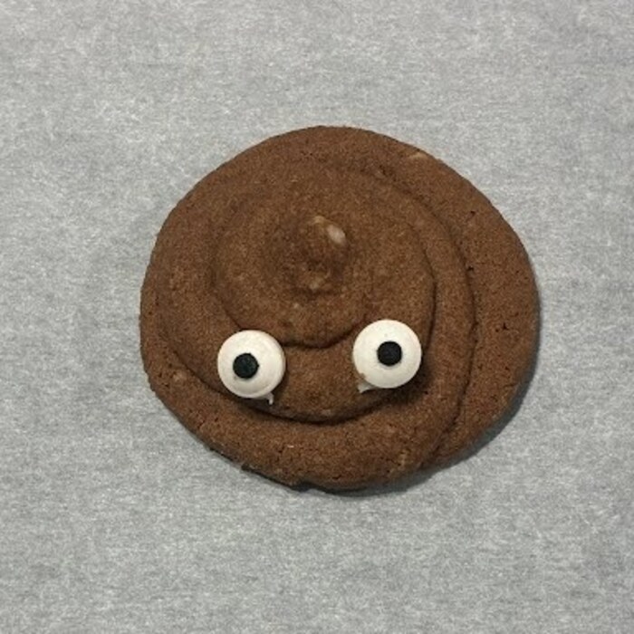 A single Dumpty's Poop Cookie with candy eyes on parchment